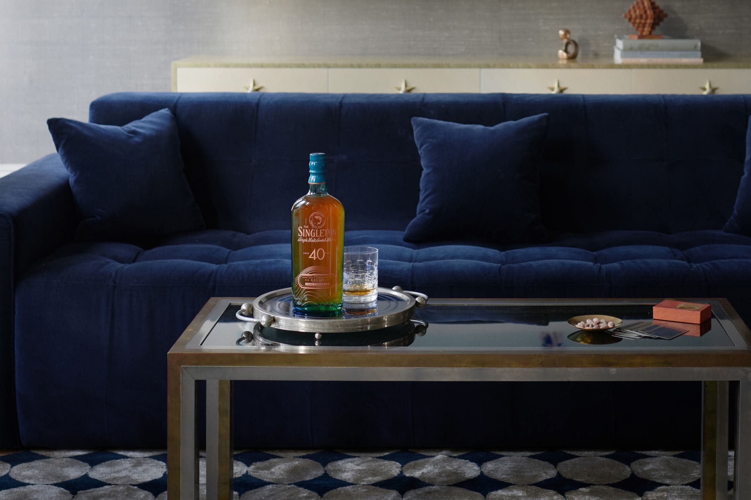 The Singleton 40 Year Old Bottle next to a luxury velvet sofa