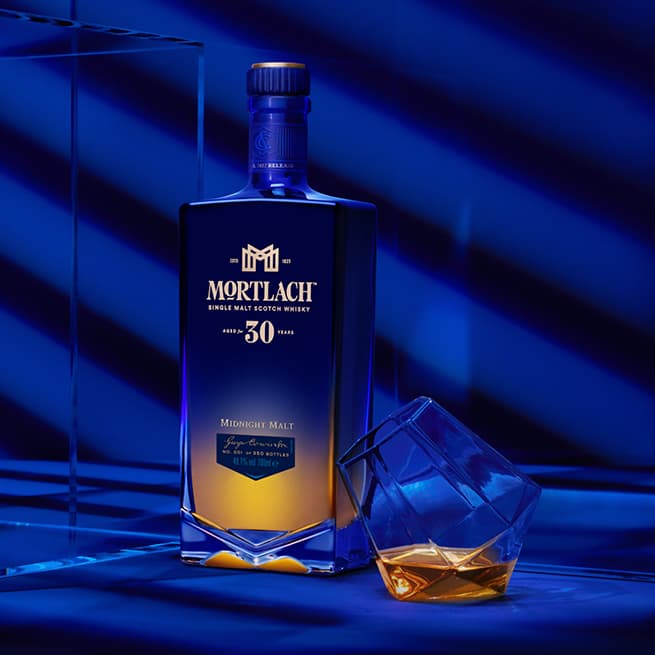 Mortlach 30​ Year Old on a table with a glass of whisky on a blue room