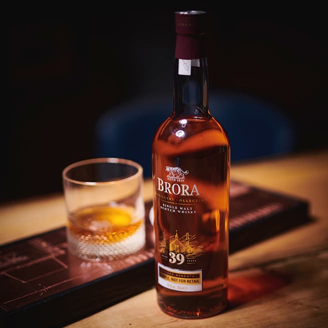 Brora 39 Year Old on a table with a glass of whisky at the back of the bottle