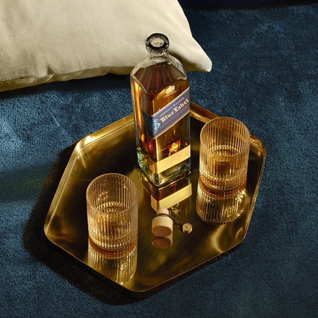 Johnnie Walker Blue Label​ on a table with two glasses of whiskies on either side of the bottle