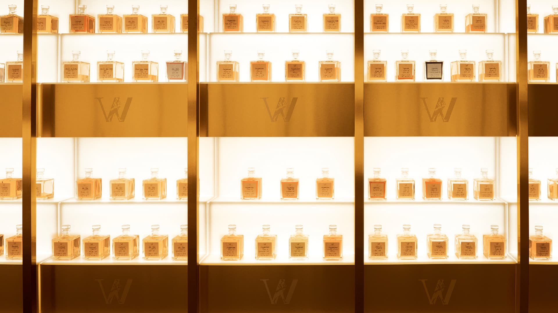 An illuminated display of elegantly arranged whiskey bottles in a golden-hued setting, featuring the iconic Johnnie Walker branding, evoking luxury and craftsmanship.