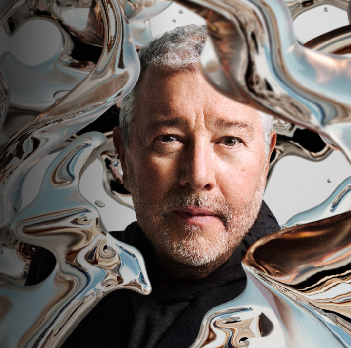 Portrait of Philippe Starck, surrounded by abstract, metallic liquid-like shapes.