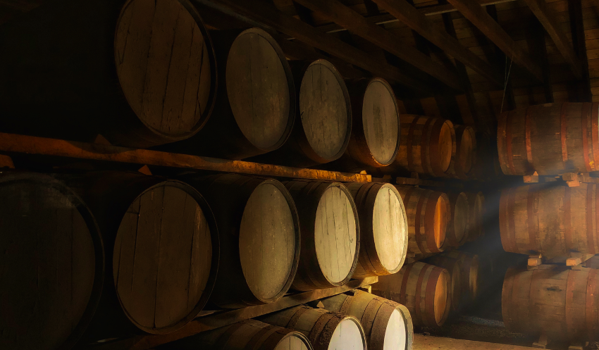 A dimly lit image of mutiple whisky casks maturing