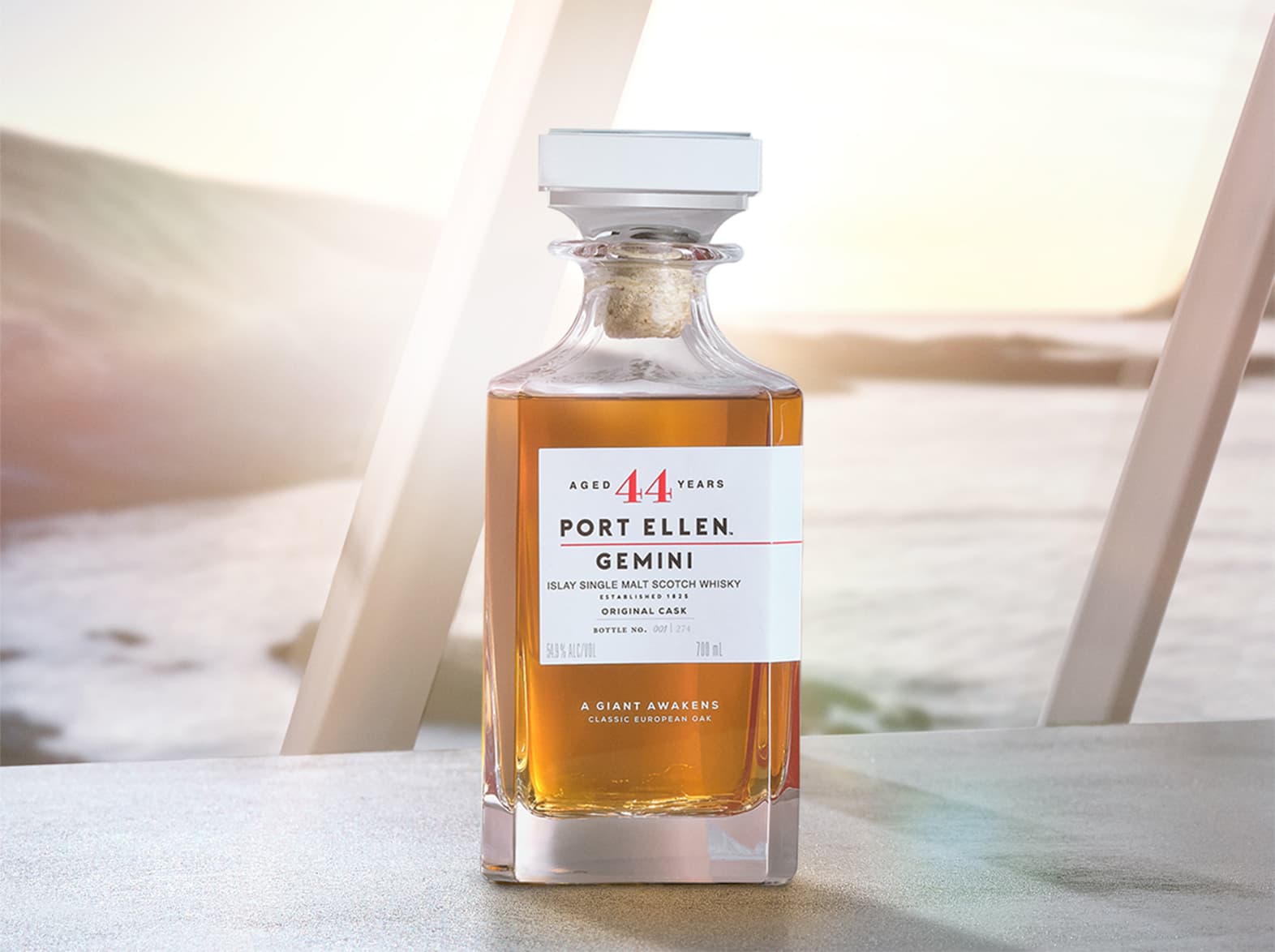 Bottle of gemini original whisky from port ellen in front of a window with ocean view
