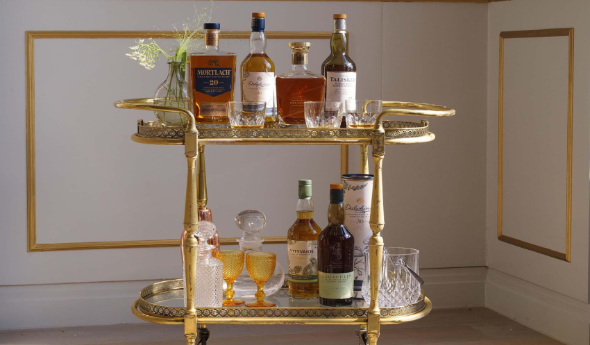 a selection of rare sptirits placed on a vintage inspired glass drinks trolley
